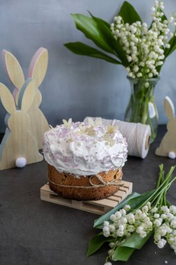 Ev yapımı Paskalya pastası kremalı ve yaratıcı dekorasyon yiyecekli panettone. Hıristiyan bayramı için hazırlık Kulich. Arka planda Paskalya yumurtası ve tavşan var. 