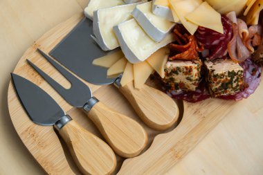 Peynir ve et şarküteri tahtası. Hediye hediyesi, öğle yemeği tabağı. Görsel olarak en az çaba gerektiren atıştırmalıklar. Özel peynir bıçaklarıyla basit bir yemek hazırlama. Tahta.