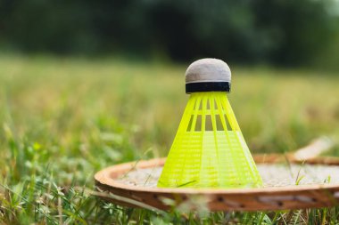 Badminton raketi ve mekik horozu yeşil çimlerin üzerinde yatar. Eğlence ve temiz hava dışında. Sağlıklı yaşam tarzı doğal bağlantı sporu yaz aktiviteleri. Stres atma hobisi sağlık hizmetleri
