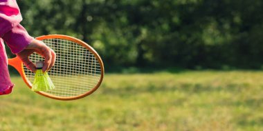 Neon sarısı badminton topu ve ahşap raket tutan bir kadın. Mekik horozlarına yumuşak seçici odak kopyala. Alternatif fitness eğlence sporu