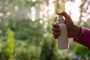 Yazın açık havada eline böcek ilacı sıkan biri var. Sivrisinekleri ve sinekleri öldürmeye çalışıyor. Bariz bir şekilde damlacıklar. Güneşli bir günde sivrisinek ısırığına karşı korunma.