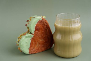Yeşil çay Matcha latte cappuccino içeceği Sabah kahvaltısı hediye fikri Fotokopi alanlı yeşil arka planda fıstık şeklinde kruvasan. Puf puf yeni moda tatlı pastanesi. Kremalı hamur