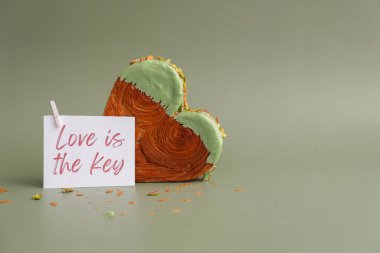 Sevgi, kâğıt üzerinde yazan anahtardır. Sabah kartı Sevgililer Günü hediyesi. Yeşil arka planda, üzerinde fotokopi alanı olan Antep fıstıklı kruvasan. Puf puf yeni moda tatlı pastanesi. Kremalı.