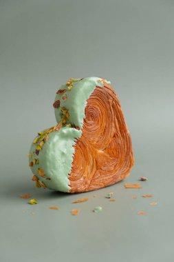 Fotokopi alanı olan yeşil arka planda kalp şeklinde şam fıstıklı kruvasan. Puf puf yeni moda tatlı pastanesi. Kremalı hamur deneyi 