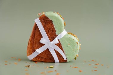 Sevgililer Günü kutlamaları için hediye olarak sunulan hediye. Yeşil arka planda, içinde fotokopi alanı olan fıstık şeklinde kruvasan. Puf puf yeni moda tatlı pastanesi. Kremalı hamur