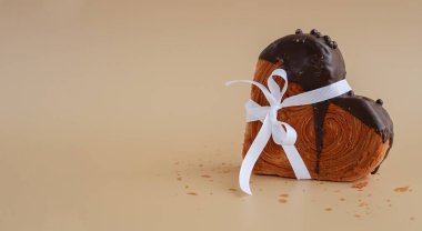 Hediye, bayram bayramı sevgililer günü kutlaması bej arka planda siyah çikolatalı kruvasan şeklinde ve fotokopi alanı. Puf puf yeni moda tatlı pastanesi. Kremalı hamur