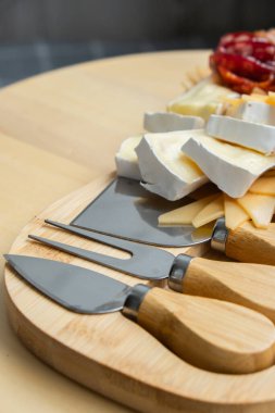 Peynir ve et şarküteri tahtası. Hediye hediyesi, öğle yemeği tabağı. Görsel olarak en az çaba gerektiren atıştırmalıklar. Özel peynir bıçaklarıyla basit bir yemek hazırlama. Tahta.