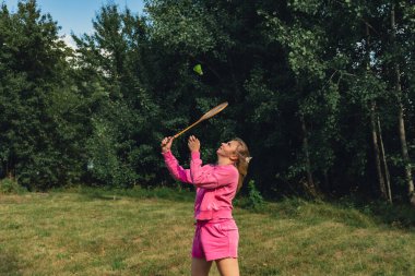 Kadın, yeşil çimlerde Badminton raketi ve mekik horozu oynuyor. Eğlence ve temiz hava dışında. Sağlıklı yaşam tarzı doğal bağlantı sporu yaz aktiviteleri. Stres atma hobisi sağlık hizmetleri