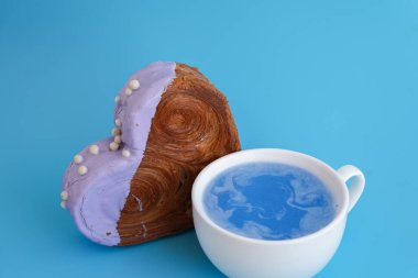 Mavi içecek Matcha içeceği süper yiyecekler Sevgililer Günü bayramı hediyesi harika ve canlı kalp şeklinde kruvasan ikram, güzel bir şekilde üzeri renkli kremayla kaplanmış.