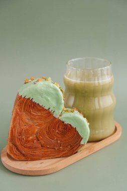 Yeşil çay Matcha latte cappuccino içeceği Sabah kahvaltısı hediye fikri Fotokopi alanlı yeşil arka planda fıstık şeklinde kruvasan. Puf puf yeni moda tatlı pastanesi. Kremalı hamur