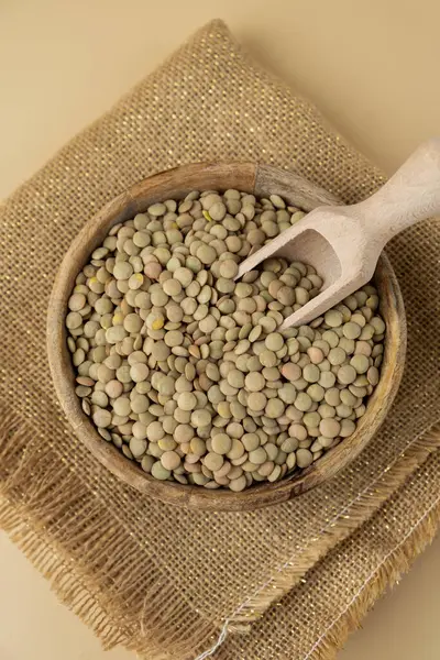 Tarafsız bej arka planda yeşil mercimek kopyalama alanı. Tam hecelenmiş tahıl türü. Yüksek proteinli lif zengini vejetaryen gıda bileşeni. Glütensiz süper yiyecek sağlıklı beslenme alternatifi