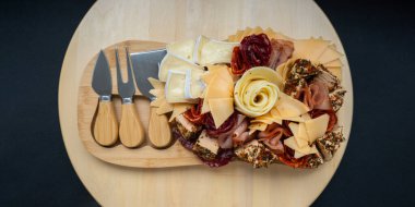 Peynir ve et şarküteri tahtası. Hediye hediyesi, öğle yemeği tabağı. Görsel olarak en az çaba gerektiren atıştırmalıklar. Özel peynir bıçaklarıyla basit bir yemek hazırlama. Tahta.