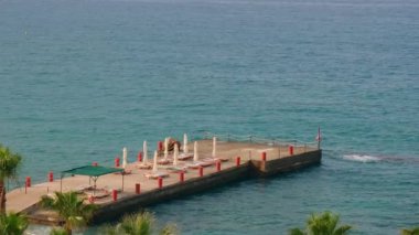 Dalgalar Antalya Türkiye 'deki ahşap iskeleye çarpıyor. Palmiyeler ve deniz seyahati turizmi konsepti. Kumsal ve dağlar. Üst görünüm. 