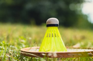 Neon sarısı badminton mekik horozu ve açık havada yeşil çimlerde raket. Mekik horozlarına yumuşak seçici odak kopyala. Alternatif fitness eğlence sporu
