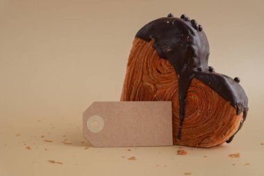 Boş kağıt not şablonu Heart şeklinde koyu çikolatalı kruvasan ve bej arka planda fotokopi alanı. Puf puf yeni moda tatlı pastanesi. Kremalı hamur deneyi 