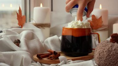 El krem şanti ekliyor. Sonbahar kremalı turuncu kahve fincanı. Sonbahar yaprakları yağmur damlalarına karşı masaya dökülüyor. Samimi düşüşün canlı görüntüleri mum yakıyor. Şükran Günü