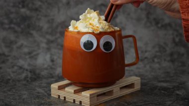 Tarçın çubukları eklemek Cadılar Bayramı dekorasyon suratıyla balkabağı aromalı latte kahveyi ısıtmak. Cadılar Bayramı için sonbahar içkileri Şükran Günü Tatil içeceği Sonbahar baharlı tarçın