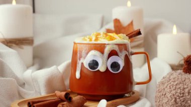 Cadılar Bayramı 'nın komik yüzleri, sonbahar şurubu portakal kupası ve sonbahar yapraklarıyla dolu bir bardağa bakar. Samimi düşüşün canlı görüntüleri mum yakıyor. Şükran Günü konsepti