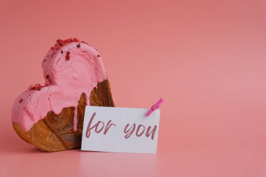 Kâğıt altlığı üzerine manşet metni. Bayram hediyesi. Kalp şeklinde çilekli kruvasan. Puf puf yeni moda tatlı pastanesi. Kremalı hamur deneyi