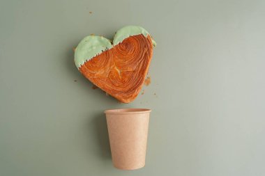 El işi kağıt bardak enfes ve canlı kalp şeklinde kruvasan şekerlemesi. Renkli fındıklı kruvasanla güzelce kaplanmış. Şablon kopyalama alanı oluşturun. Gıda deneyleri viral tatlı