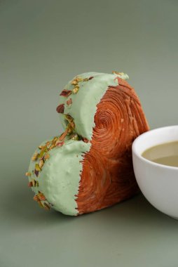 Yeşil çay Matcha latte cappuccino içeceği Sabah kahvaltısı hediye fikri Fotokopi alanlı yeşil arka planda fıstık şeklinde kruvasan. Puf puf yeni moda tatlı pastanesi. Kremalı hamur