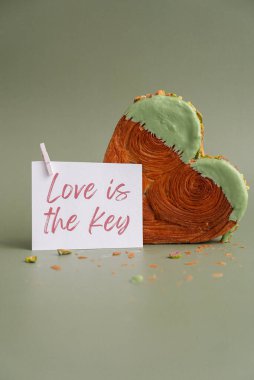 Aşk, Sevgililer Günü tebrik kartında yazan anahtar manşettir. Lezzetli ve canlı kalp şeklinde pasta şeklinde kruvasan. Renkli kremalı fındık dolu. Şablon kopyasına uydur