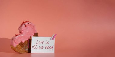 Sevgililer Günü Aşkı tek ihtiyacımız olan şey tebrik kartının başlığı. Lezzetli ve canlı kalp şeklinde kruvasan ikram. Renkli kruvasanlarla süslenmiş. Uzayı kopyala Yiyecek.