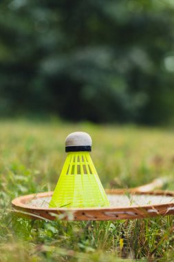 Neon sarısı badminton mekik horozu ve açık havada yeşil çimlerde raket. Mekik horozlarına yumuşak seçici odak kopyala. Alternatif fitness eğlence sporu