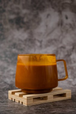 Balkabağı aromalı latte sabah kahvesi. Cadılar Bayramı için Sonbahar İçkileri Şükran Günü Tatil içeceği Sonbahar baharatlı tarçın aromalı sıcak mevsimlik sıcak içecekler sıcak turuncu bardakta. Soğuk yağmurun atmosferi