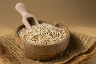 Tarafsız bej arka planda inci arpa. Tam hecelenmiş tahıl türü. Yüksek proteinli lif zengini vejetaryen gıda bileşeni. Glütensiz süper yiyecekler sağlıklı beslenme alternatifleri 