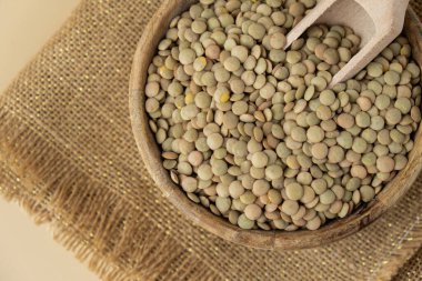 Tarafsız bej arka planda yeşil mercimek kopyalama alanı. Tam hecelenmiş tahıl türü. Yüksek proteinli lif zengini vejetaryen gıda bileşeni. Glütensiz süper yiyecek sağlıklı beslenme alternatifi