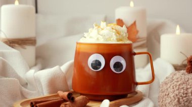 Cadılar Bayramı 'nın komik yüzleri, sonbahar şurubu portakal kupası ve sonbahar yapraklarıyla dolu bir bardağa bakar. Samimi düşüşün canlı görüntüleri mum yakıyor. Şükran Günü konsepti