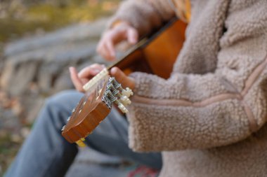 Sonbahar ormanlarında dışarıda gitar çalarak ellerinizi kapatın. Ses terapisi, akıl sağlığı ve sağlık ayinleri kavramı. Sakinlik sükuneti ses duyusal uygulamaları. Aura tarım enerjisi