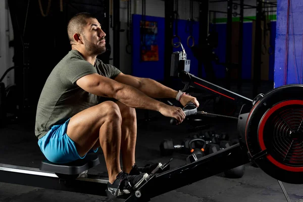 man in sportswear rowing on a machine in a gym