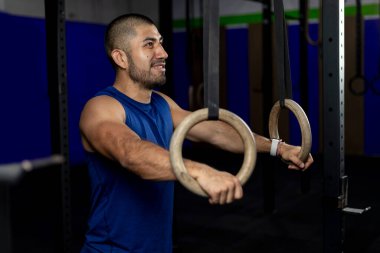 Eğitim sahasında jimnastik yüzüklerine yaslanan bir sporcunun portresi