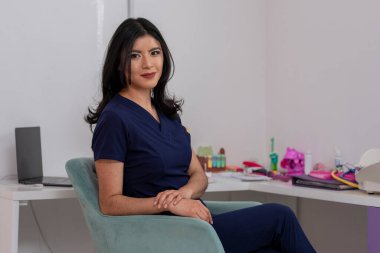 Genç Meksikalı doktor, bürosunun masasında oturmuş fotokopi makinesiyle kameraya bakıyor..