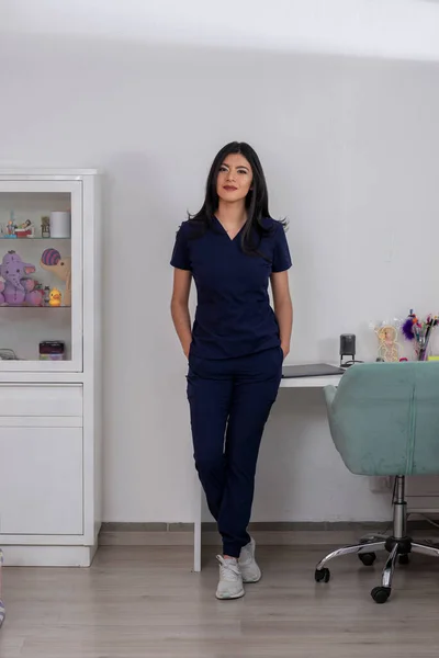 Young Latina doctor in her office, full-length portrait