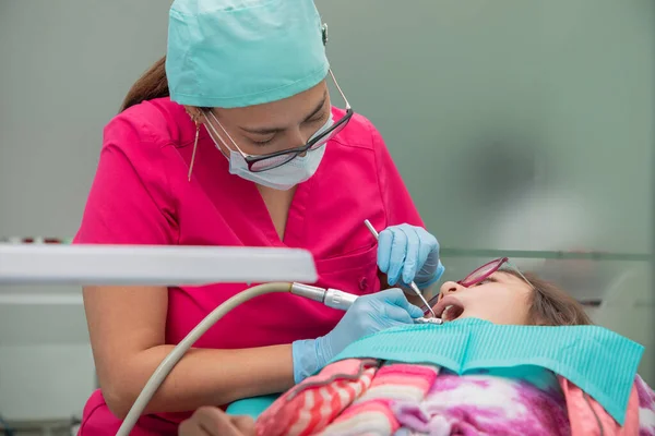 牙医在她的牙科诊所清洁女孩的牙齿 — 图库照片