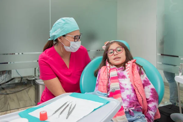 女牙医在她的医务室接受牙科治疗时看着她的病人 — 图库照片