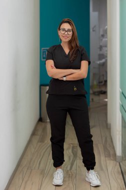 Üniformalı bir portre dişçisi kliniğin koridorundaki kameraya bakıyor.