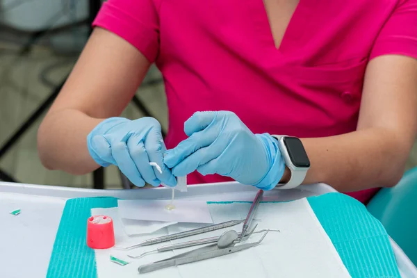 牙医的手 从她盘子里倒出一个装有氟化物的信封 用在病人身上 — 图库照片