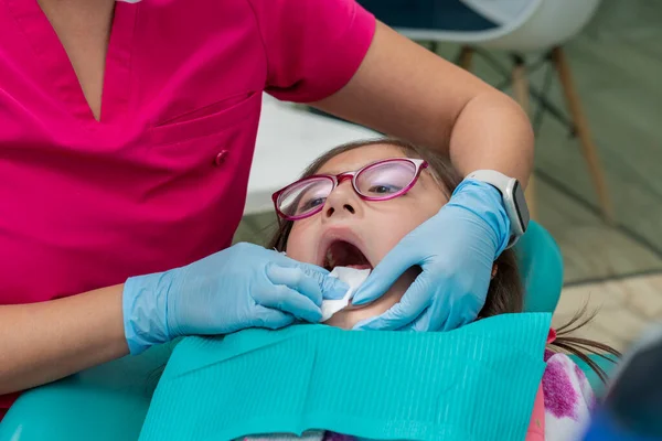 牙医用纱布清洁女孩的牙齿后 用牙刷清洁她的牙齿 — 图库照片