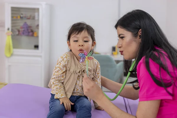 Una Niña Que Sopla Molinete Mientras Examinada Por Pediatra Consultorio — Foto de Stock