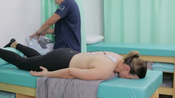 Mujer Acostada Camilla Con Almohadillas Electrodos Espalda Recibiendo Terapia Fisioterapeuta — Vídeo de stock