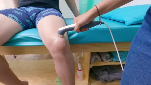 患者の膝に超音波治療を施す理学療法士の手を閉じて — ストック動画