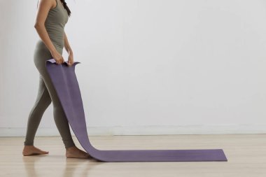 Tanımlanamayan kadın dersten sonra yoga minderini kaldırıyor.