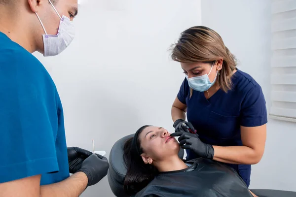 应用透明质酸唇疗法治疗年轻妇女的美容师 — 图库照片