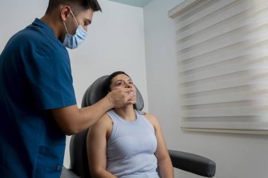 Bir güzellik uzmanı genç bir kadının dudaklarını temizler. Dudaklarına güzellik tedavisi uygular.