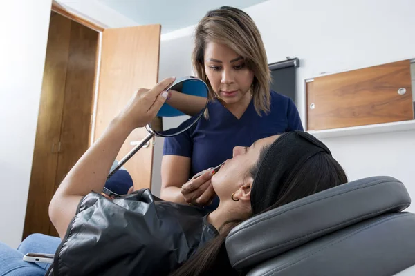 当一位美容师准备给她注射透明质酸时 医务室里的年轻妇女看着她的嘴唇 — 图库照片