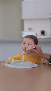 Büyükannesi onu kaşıkla beslerken çocuk evde kahvaltı yapıyor.
